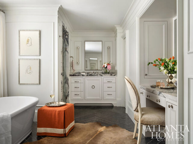White bathroom with freestanding tub, orange ottoman, vanity, and makeup chair