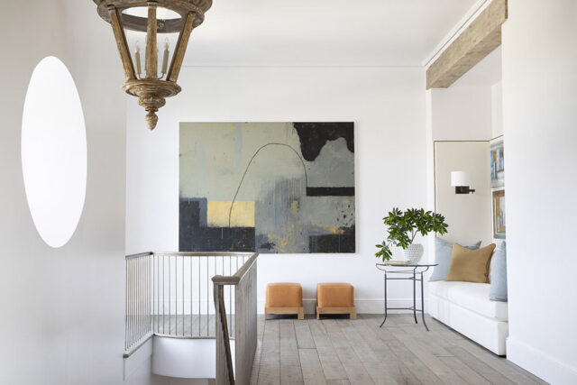 Hallway with abstract art, wooden chandelier, and built-in bench seating.