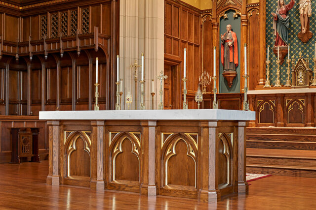Church altar with marble top and ornate wooden base, featuring brass candlesticks and religious