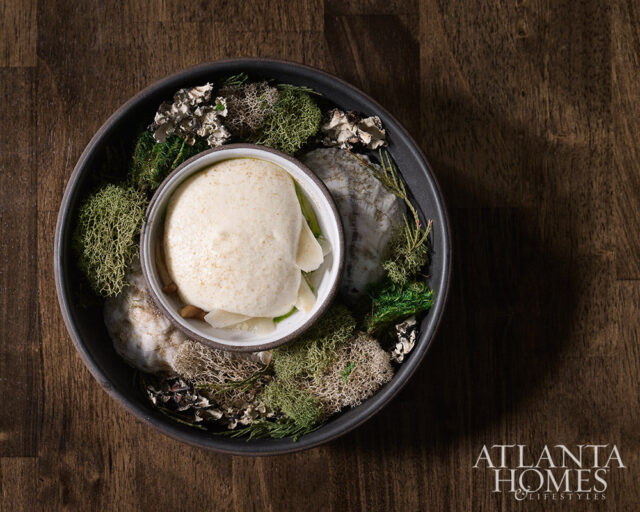 Creamy food in a bowl surrounded by moss and natural elements