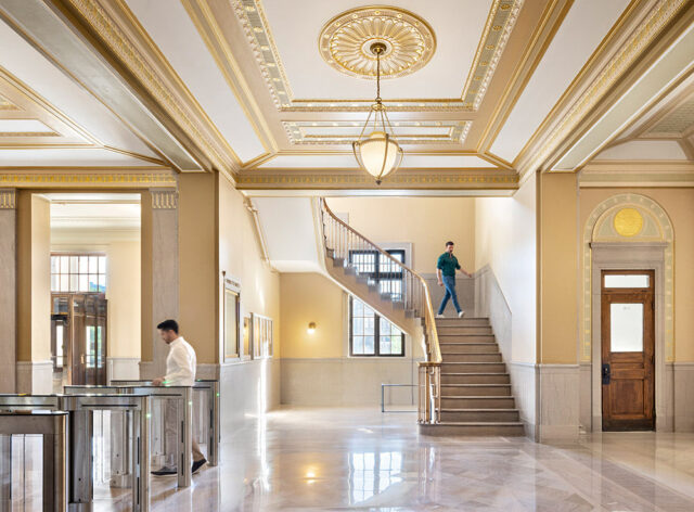 Lobby with ornate gold and white ceiling, marble floors, and a grand staircase.