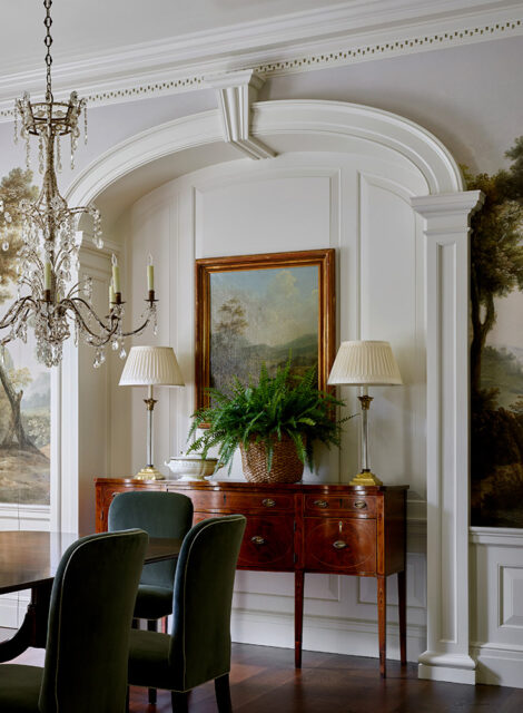 Dining room with dark wood buffet, landscape painting, and crystal chandelier