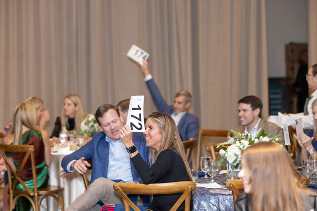Woman holding paddle 172 at auction event. Man holds paddle 174.