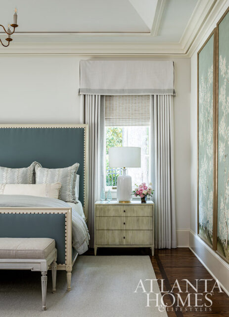 Bedroom with teal upholstered bed, light grey rug, and chinoiserie wall art.