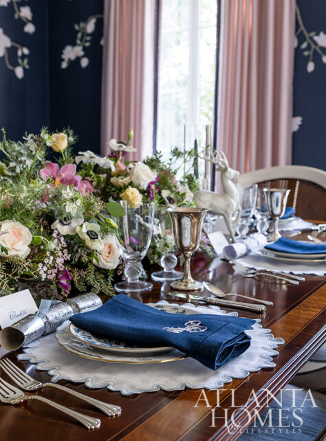 Dining table set with blue napkins, floral centerpiece, and deer figurine.