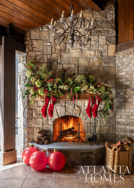 Stone fireplace with Christmas decorations, stockings, and a fire burning.