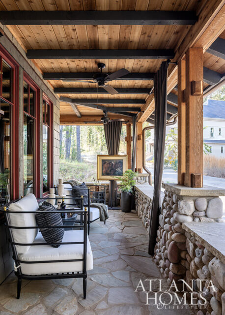 Covered porch with stone floor, wood ceiling, black ceiling fans, and seating.