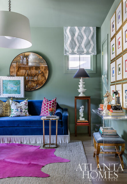 Living room with blue velvet sofa, pink hide rug, and gallery wall