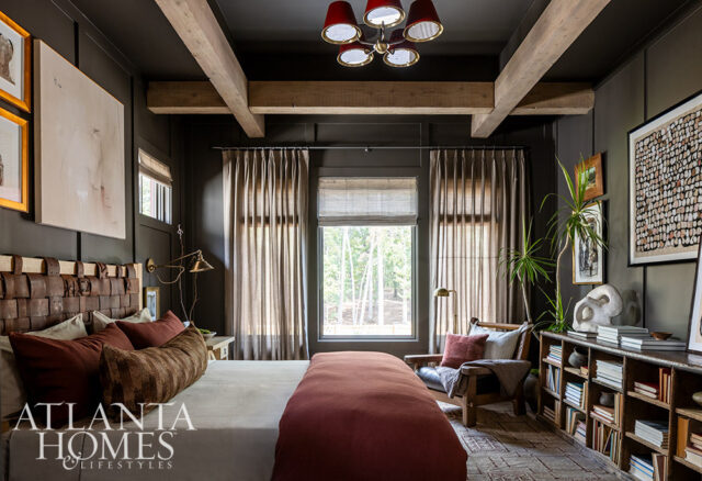 Bedroom with dark walls, wood beams, leather headboard, and rust-colored bedding.
