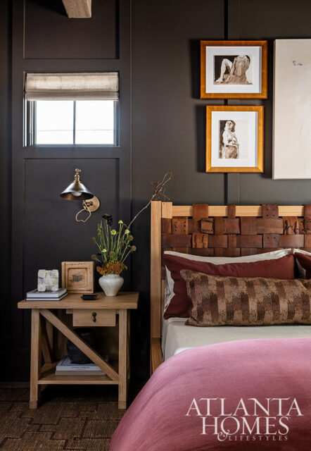 Bedroom with dark walls, wood nightstand, leather headboard, and pink bedding.