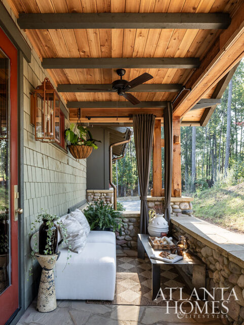 Covered porch with white sofa, stone accents, wood ceiling, and Atlanta Homes & Lifestyles logo.