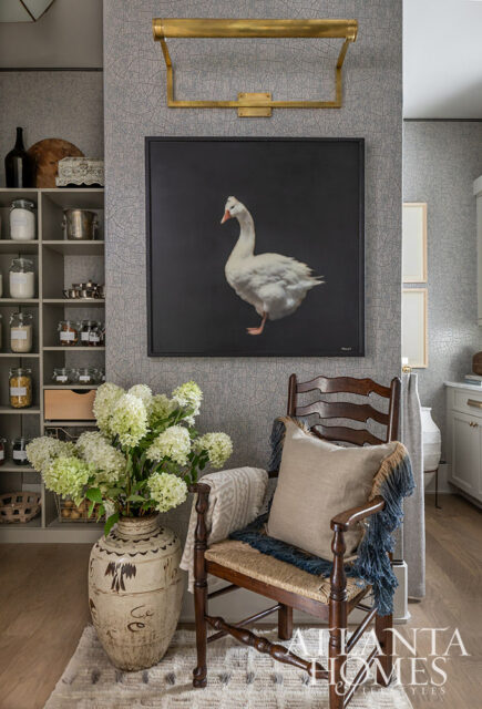 Gray textured wallpaper with framed painting of a white goose above a wooden chair with a pillow