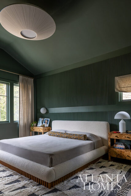 Green bedroom with a white textured bed, fluted wall paneling, and a large circular ceiling light