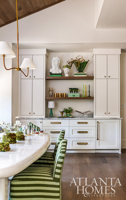 White built-in cabinets with marble countertop, brass hardware, and decorative busts and vases.