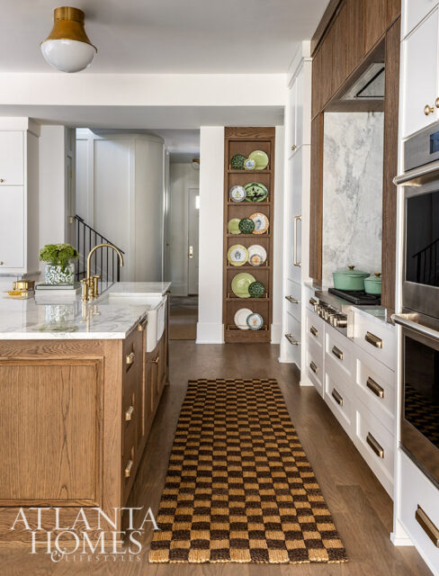Kitchen with white cabinets, wood island, marble countertops, and checkered rug