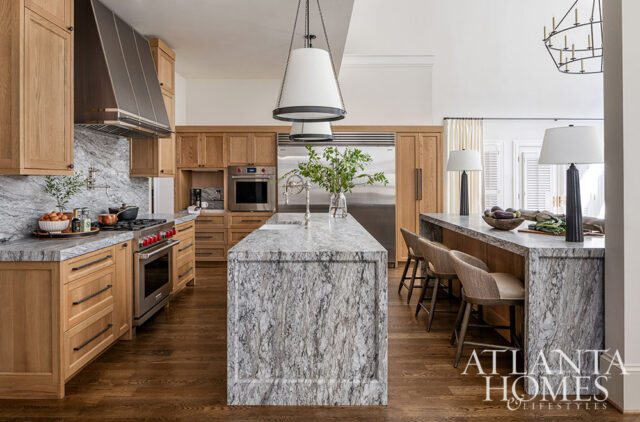Kitchen with light wood cabinetry, marble countertops, and a large island.