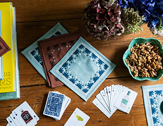 Blue and brown embroidered cocktail napkins with playing cards and walnuts on a wooden table