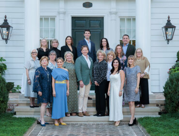 Group of people posing on the steps of a white house
