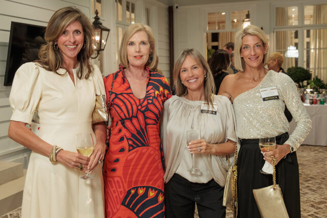 Four women holding drinks at an event. One woman wears a sequined top.