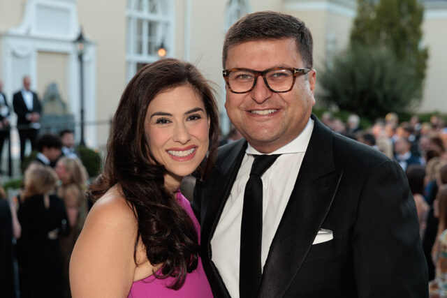 Man in glasses and tuxedo with woman in pink dress smiling