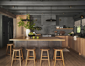 Rustic kitchen with wood island, four stools, dark gray walls, and exposed beams.