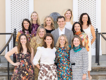 Group portrait of eleven people posing outdoors on steps.