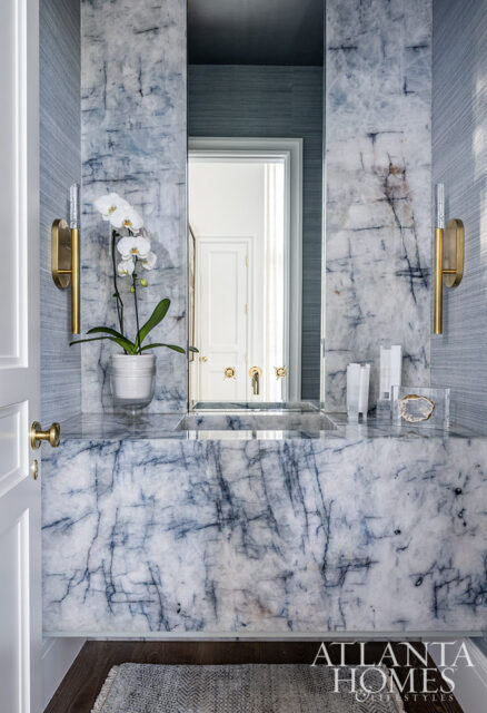 Powder room with blue marble vanity, integrated sink, and grasscloth wallpaper.