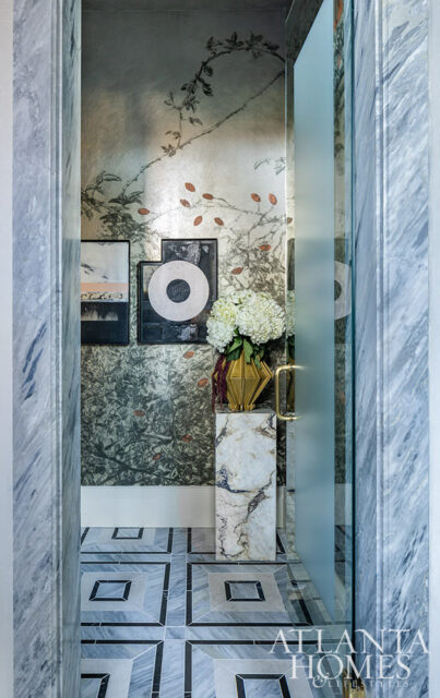 Hallway with marble floors, botanical wallpaper, and framed art. Frosted glass door.