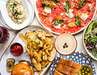 Assortment of food including shrimp, carpaccio, fries, burger, salad, bread, and coffee
