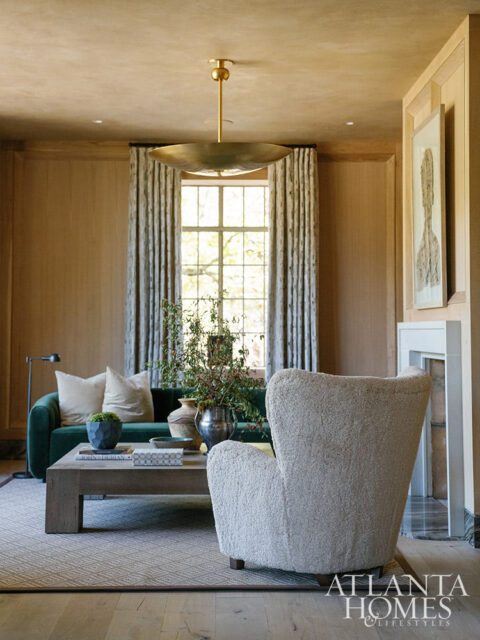 Living room with green sofa, textured armchair, wood coffee table, and large window
