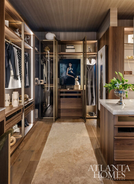 Walk-in closet with dark wood cabinetry, marble island, and artwork.