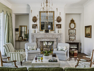 Living room with marble fireplace, striped armchairs, floral upholstered chairs, and ornate