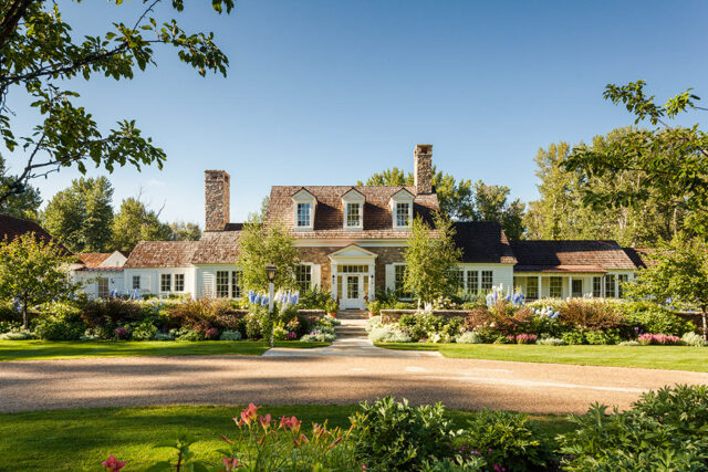 Stone and white clapboard house with cedar shake roof and dormer windows.