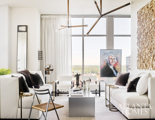 Living room with white sofas, modern art, and large windows overlooking a city skyline