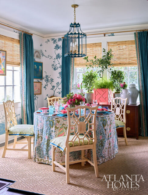 Dining room with blue chinoiserie wallpaper, bamboo blinds, and a round table with a floral