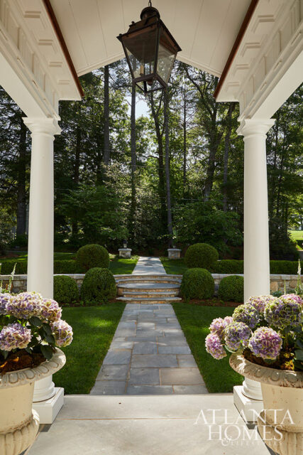 Stone pathway through manicured garden with hydrangeas and topiaries