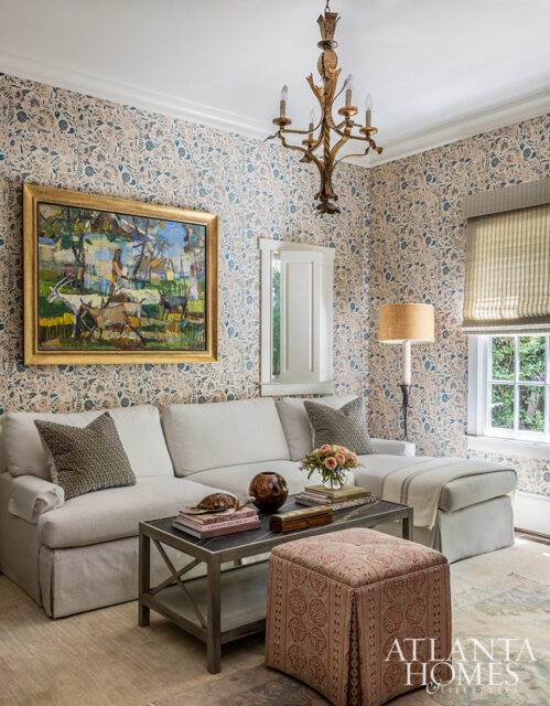 Living room with floral wallpaper, sectional sofa, and ornate chandelier.