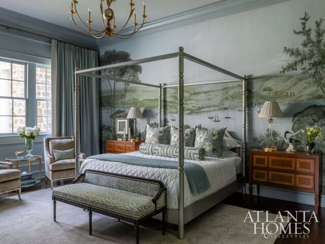 Bedroom with a four-poster bed, landscape mural wallpaper, upholstered armchairs, and a decorative bench.