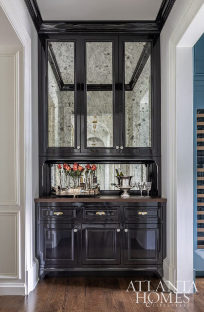 Black lacquered cabinet with mirrored doors, a dark wood countertop, and a silver tray with roses and wine bottles