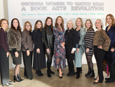 Group portrait of ten women standing in front of a wall with text that reads 'GEORGIA WOMEN TO WATCH 2026: A BOOK ARTS REVOLUTION' and names including Eliza Bentz, Hannah Israel, Cynthia Lollis, Serena Perrone, and Eileen Wallace.