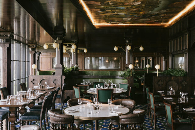 Restaurant dining room with dark wood paneling, green banquettes, and a mural on the ceiling.