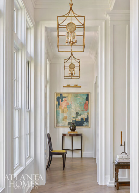 Hallway with gold lanterns, abstract art, and a dark wood chair