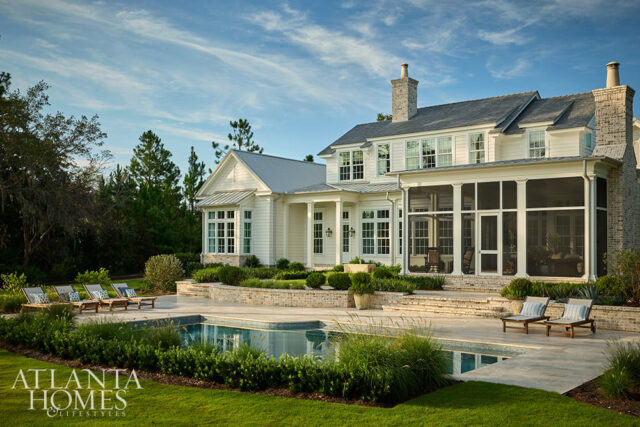 White house with screened porch, pool, lounge chairs, and manicured lawn