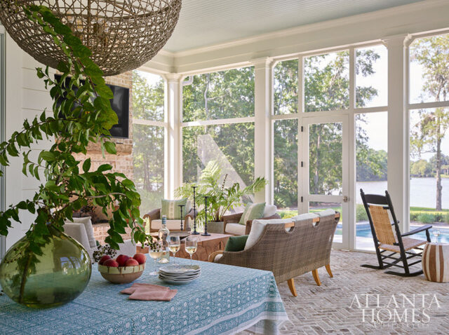 Sunroom with wicker furniture, brick fireplace, and view of lake
