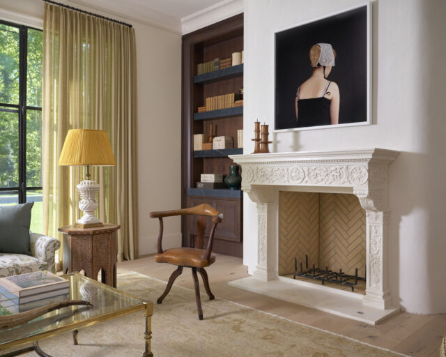 Living room with ornate fireplace, built-in bookshelves, and artwork of a woman in a bonnet.