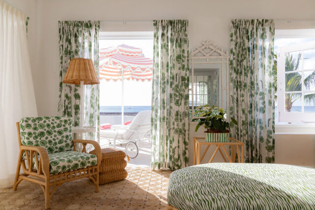 Rattan armchair with green leaf pattern cushions, wicker ottoman, and green zebra print ottoman.