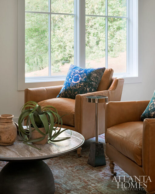 Living room with two tan leather armchairs, a marble coffee table, and a dark blue patterned pillow.