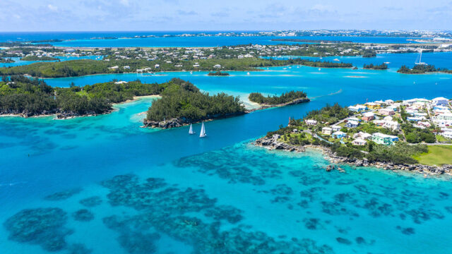 Aerial view of Bermuda with turquoise water, sailboats, and colorful houses on islands.