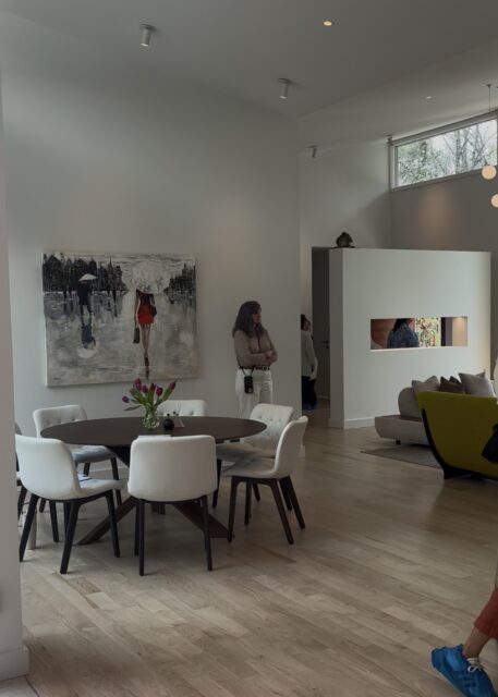 Dining area with oval table, white chairs, and abstract art. Modern living space.