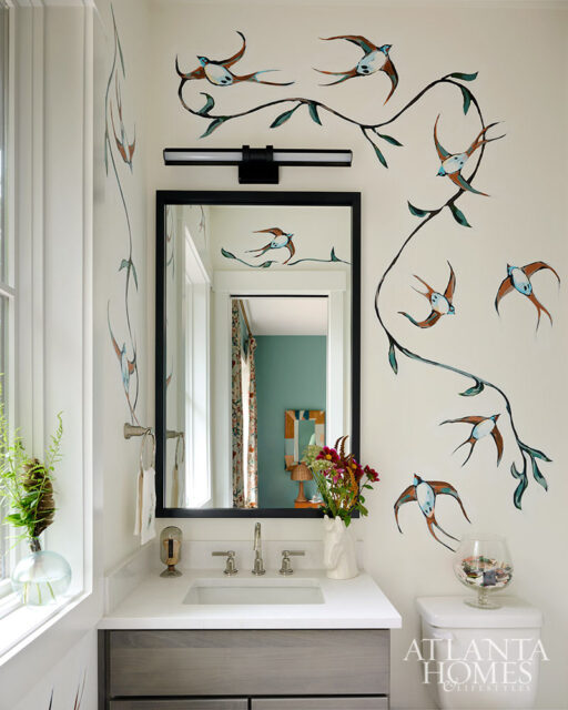 Bathroom with bird and branch wallpaper, vanity with white countertop, and black framed mirror.